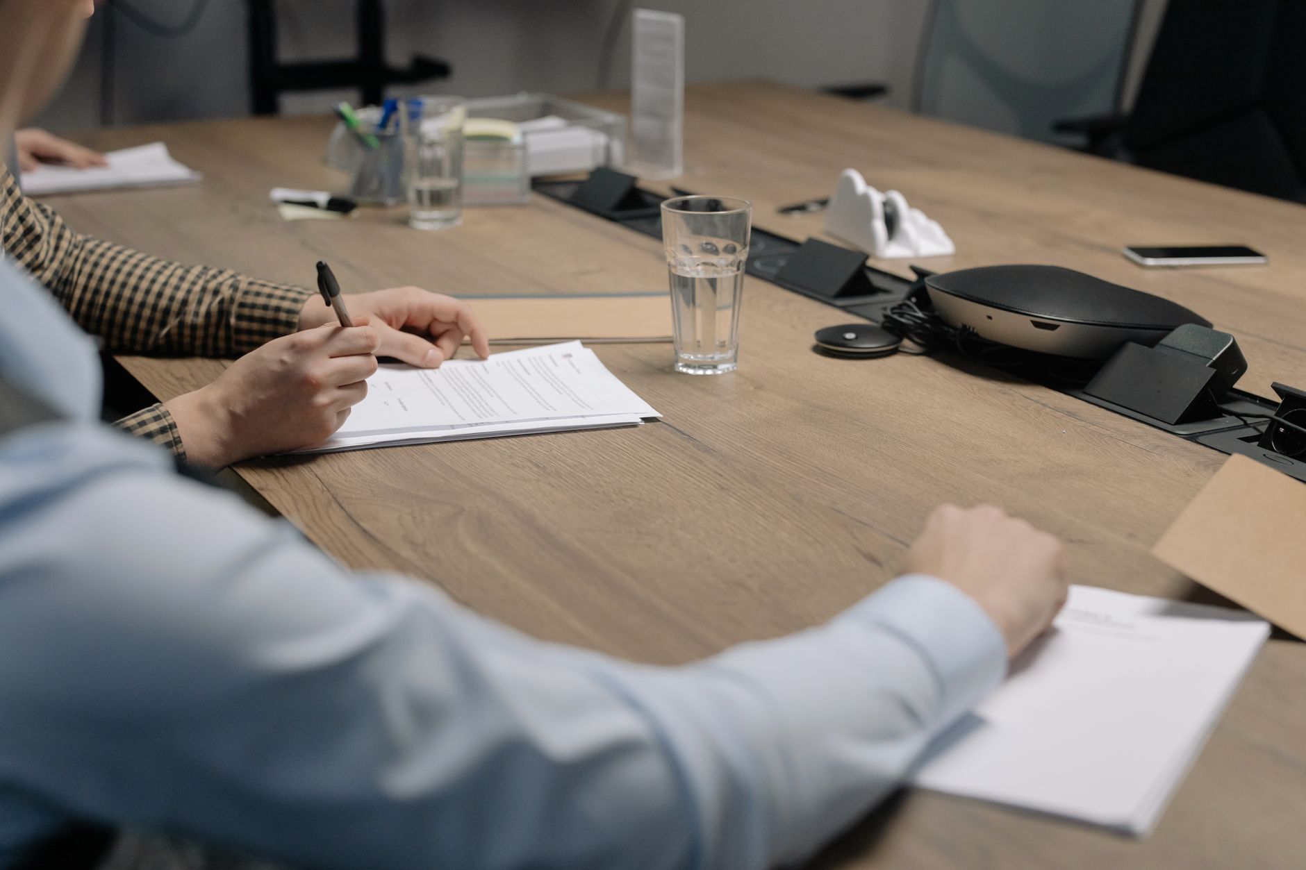 Advisers and a client signing regulatory documents across a boardroom table